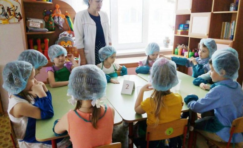 Педагог и дети в медицинских шапочках