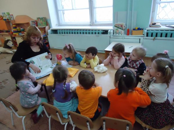 Воспитатель показывает детям за столом книжку
