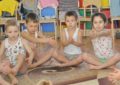 Четверо детей выполняют упражнение, сидя на полу