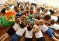 Дети и педагог в костюме клоуна с мячиками лежат на полу