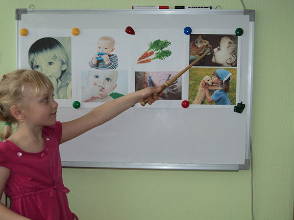 Девочка показывает указкой на картинки на магнитной доске
