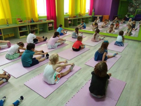 Дети выполняют упражнения, сидя на ковриках