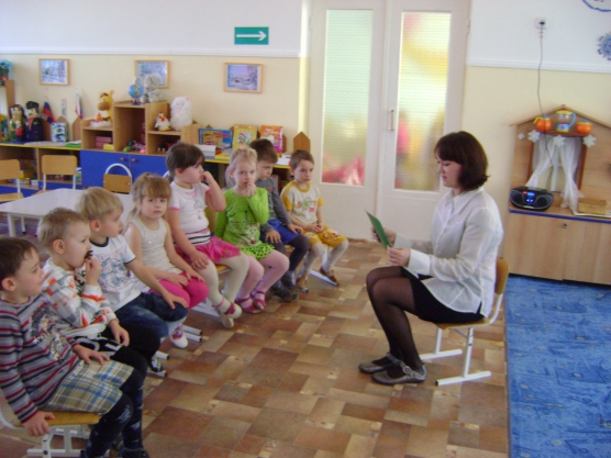 Педагог читает детям, сидящим напротив