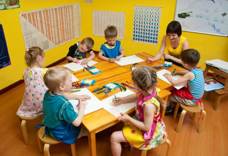 Дети с педагогом рисуют за столом