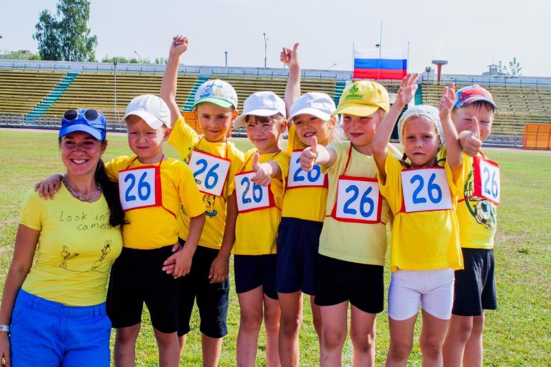 Педагог и дети в жёлтых футболках на стадионе