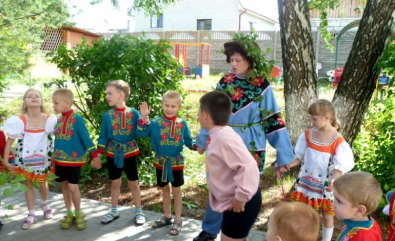 Воспитательница в костюме со шляпой с дети в национальных костюмах
