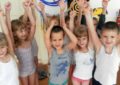 Дети в маечках стоят, подняв руки вверх