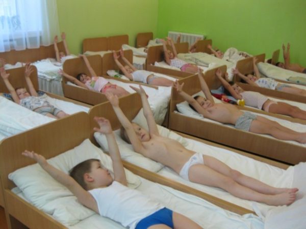Дети лежат в кроватках, руки подняли вверх