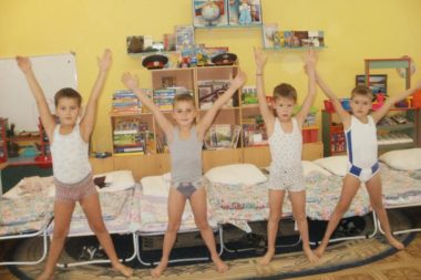 Четыре мальчика стоят после сна, держат руки вверх