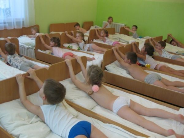 Дети лежат на животах, держатся за спинку кроватей
