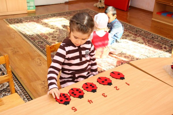 Девочка изучает цифры с помощью картонных божьих коровок