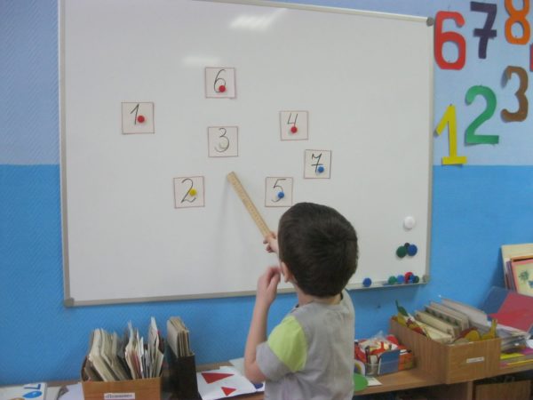 Мальчик стоит у доски и показывает на цифру «3»