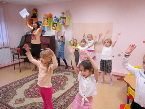 Дети и педагог танцуют, подняв руки вверх