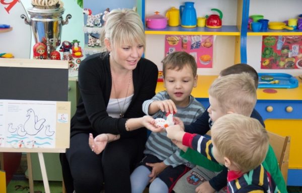 Дети изучают фигурку курочки в руках педагога