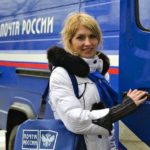 Почтальон открывает дверь машины с надписью Почта России