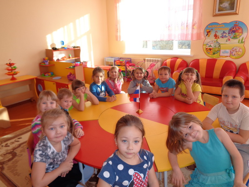 Дети сидят за круглым красно-оранжевым столом