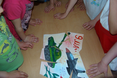 Дети стоят над пазлом-рисунком танка и самолёта