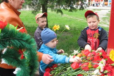 Дети с педагогом возлагают цветы к мемориалу
