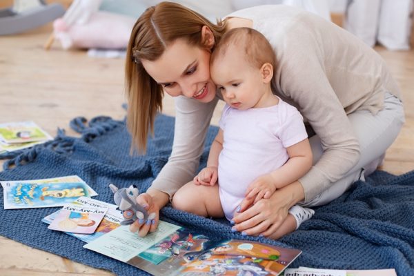 Мама читает младенцу книжку и показывает картинки