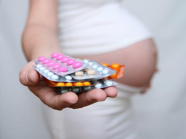 Беременная держит в руке таблетки