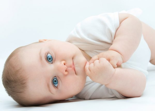 Малыш с голубыми глазами лежит на боку